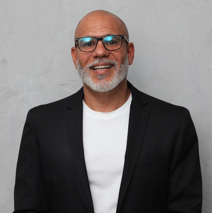 Pastor Bruno Monteiro sorrindo, de blazer preto e camiseta branca